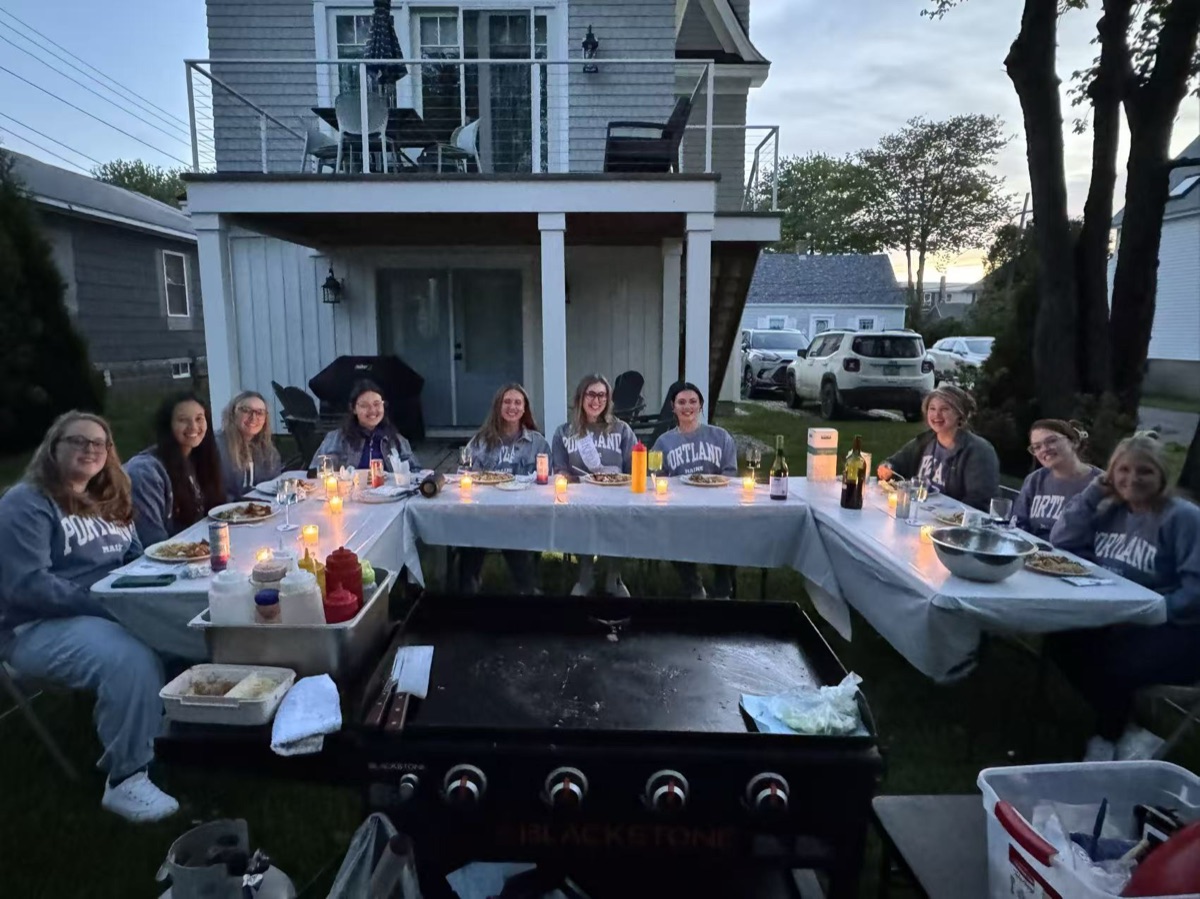 Evening backyard hibachi dinner party with guests around the grill in New England